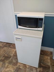 a microwave sitting on top of a white refrigerator at Motel & Camping Fort Ramsay in Gaspé