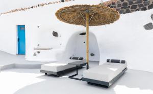 un tavolo con sedie e un ombrellone in una stanza di Rafael' s Mediteranian Cave Suites a Firostefani