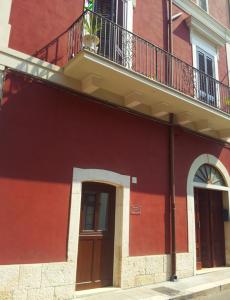 a red building with a balcony and a door at Suite Carducci B&B - Residence in Rutigliano