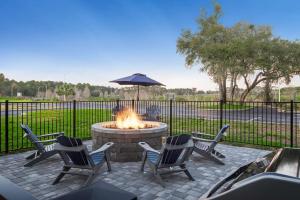 a fire pit with four chairs and an umbrella at Hampton Inn Debary-Deltona in DeBary
