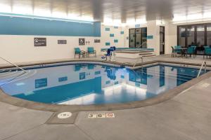 a swimming pool in a building with blue chairs and tables at Hilton Garden Inn Denver/Thornton in Thornton