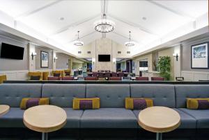 a waiting room with a blue couch and tables at Homewood Suites by Hilton Denver International Airport in Aurora