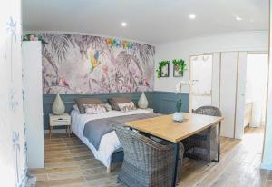 um quarto com uma cama, uma mesa e um quadro em Le colibri em Cazaubon