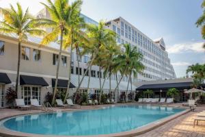 a swimming pool in front of a hotel with palm trees at DoubleTree by Hilton Hotel Deerfield Beach - Boca Raton in Deerfield Beach