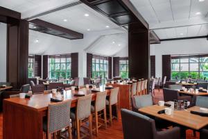 a restaurant with wooden tables and chairs and windows at DoubleTree by Hilton Hotel Deerfield Beach - Boca Raton in Deerfield Beach
