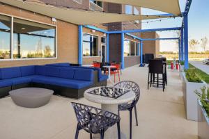 patio z niebieską kanapą, krzesłami i stołami w obiekcie Tru By Hilton Coppell DFW Airport North w mieście Coppell