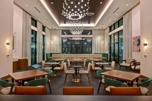 a restaurant with tables and chairs and a chandelier at Homewood Suites by Hilton Dallas The Colony in The Colony