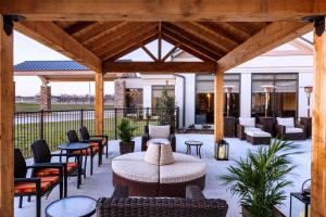 eine überdachte Terrasse mit Stühlen, Tischen und einem Tisch in der Unterkunft Hilton Garden Inn Denison/Sherman/At Texoma Event Center in Sherman