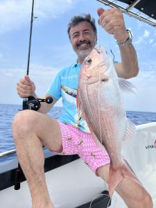 a man sitting on a boat holding a fish at Big Fishing Marmaris - Turkey Fishing Charter in Marmaris