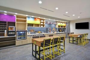 a restaurant with a bar with yellow chairs and tables at Home 2 Suites By Hilton Fairview Allen in Fairview