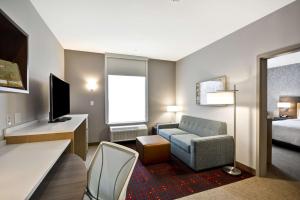 a hotel room with a bed and a couch and a chair at Home 2 Suites By Hilton Fairview Allen in Fairview