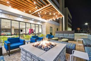 a fire pit in a lobby with chairs and tables at Home 2 Suites By Hilton Fairview Allen in Fairview