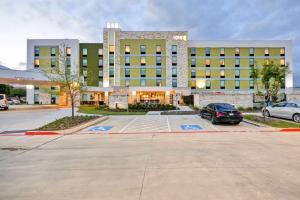 ein Parkplatz vor einem großen Gebäude in der Unterkunft Home2 Suites By Hilton Dallas Addison in Addison