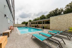 a swimming pool with chaise lounge chairs next to a building at Home2 Suites By Hilton Fort Worth Northlake in Roanoke