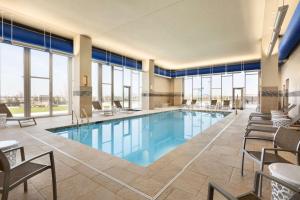 einen Pool in einem Hotel mit Stühlen und Fenstern in der Unterkunft Embassy Suites By Hilton Denton Convention Center in Denton