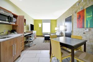 Home2 Suites By Hilton Fort Worth Southwest Cityview في فورت وورث: مطبخ وغرفة معيشة مع طاولة وكراسي