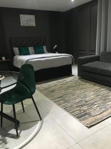 a bedroom with a bed and a chair and a couch at Black Rose Guesthouse in Soweto