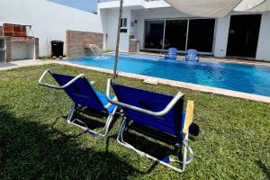 dos sillas azules sentadas en el césped cerca de una piscina en Las Villas Taxisco en Taxisco