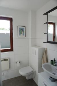 a white bathroom with a toilet and a sink at Wohnen im alten Standesamt in Pasewalk