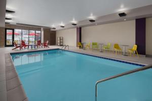 a pool in a hotel room with chairs and tables at Home2 Suites by Hilton Des Moines at Drake University in Des Moines