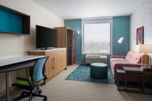 um quarto de hotel com um sofá, uma secretária e uma televisão em Home2 Suites by Hilton Des Moines at Drake University em Des Moines