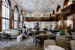 a lobby with tables and chairs and a chandelier at Hotel Fort Des Moines, Curio Collection By Hilton in Des Moines