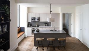 a kitchen with white cabinets and a island with stools at ROOST Midtown in Philadelphia