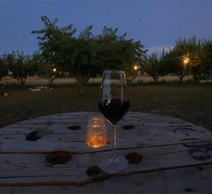 a glass of wine sitting on a table with a candle at Home Shanti, relax tra i ciliegi in Crespellano