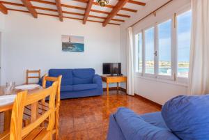 ein Wohnzimmer mit einem blauen Sofa und einem Tisch in der Unterkunft Voramar Waterfront in Sant Lluís