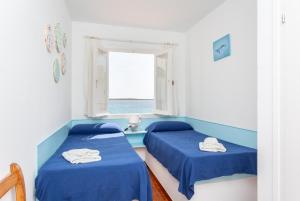dwa łóżka w pokoju z oknem w obiekcie Voramar Waterfront w mieście Sant Lluis