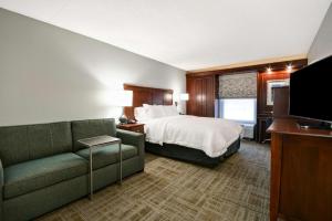 Northvilleにあるハンプトン イン デトロイト ノースヴィルのベッド、ソファ、テレビが備わるホテルルームです。