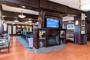 un vestíbulo con chimenea y un bar con sillas en Hampton Inn Detroit Roseville, en Clinton