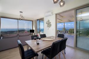 a dining room with a table and chairs and windows at Villa Lassi Fos in Kefallonia