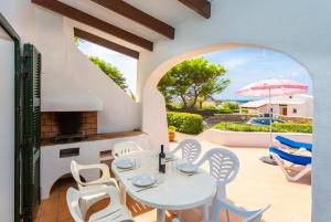 een patio met een tafel en stoelen en een parasol bij Villa Binibety in Binibeca