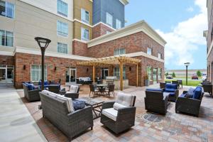 un patio avec des chaises et des tables en face d'un bâtiment dans l'établissement Homewood Suites By Hilton Warren Detroit, à Warren