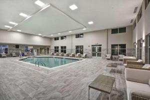 a pool in the middle of a large room with tables and chairs at Homewood Suites By Hilton Warren Detroit in Warren