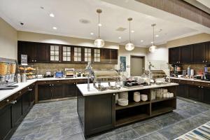 a large kitchen with dark wood cabinets and white counter tops at Homewood Suites By Hilton Warren Detroit in Warren