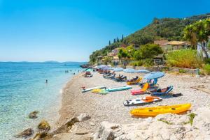 een groep mensen op een strand met parasols en boten bij Villa Georgios in Plátonas