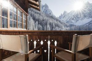 une chambre avec deux chaises, une fenêtre et des montagnes dans l'établissement Hotel Dolomitenhof & Chalet Alte Post, à Sesto