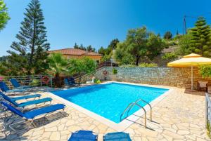 a swimming pool with chairs and an umbrella at Dolphin Villa 1 in Porto Ozias