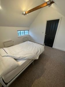 uma cama branca num quarto com uma porta preta em The Pump House em St Ives