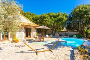 um quintal com piscina e uma casa com baloiço em Villa Nionios em Vlachopoulátika