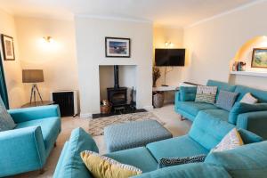 a living room with blue couches and a fireplace at Percy Cottages No4 in Alnmouth