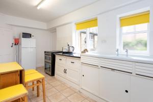 cocina con armarios blancos, fregadero y nevera en Percy Cottages No4, en Alnmouth