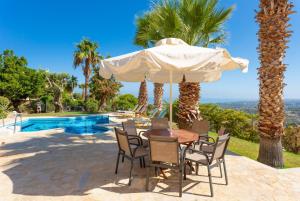 a table and chairs under an umbrella next to a pool at Villa Astro in Agia Triada