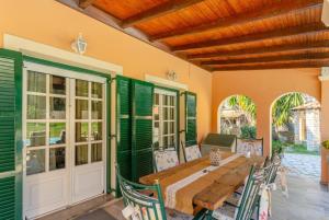 uma sala de jantar exterior com uma mesa de madeira e cadeiras em Villa Durrell em Kontokali