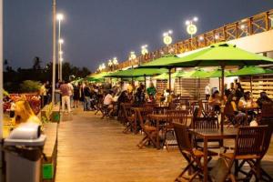 a deck with tables and green umbrellas at night at Helbor My Way - Compactos de luxo in Fortaleza