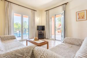 a living room with a couch and a table and a tv at Villa Youla in Nisaki