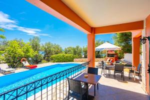 a patio with a swimming pool and a table and chairs at Villa Youla in Nisaki