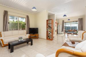 een woonkamer met witte meubels en een televisie bij Villa Solon in Peyia